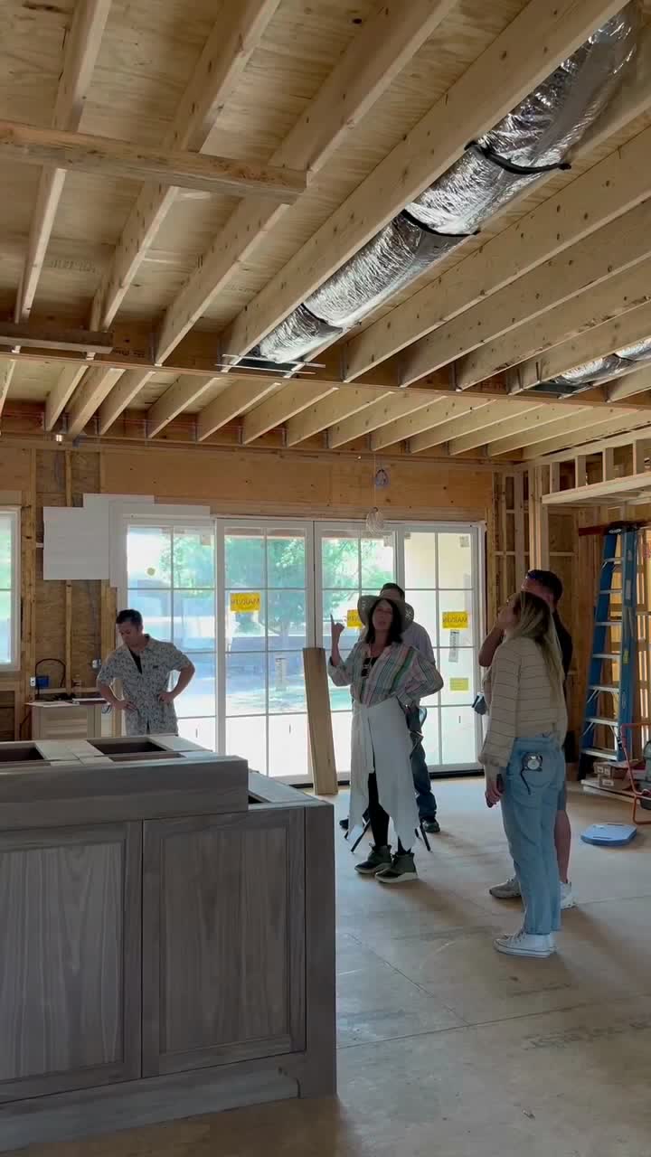 A kitchen island set in place inside a framed house, with the crew walking the site.