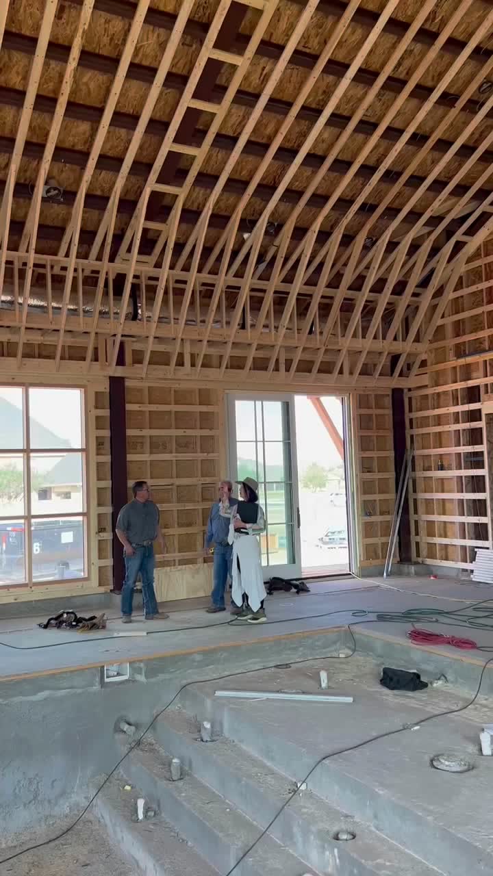 Open framing under a vaulted roof, with plumbing stubbed up through the floor.